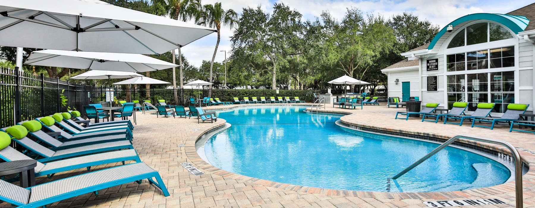 Pool deck surrounded by lounge chairs and umbrellas