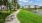a path with grass and trees by a body of water